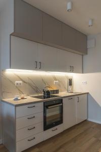 a kitchen with white cabinets and a stove top oven at Apartament Pełczyńskiego 3 in Warsaw
