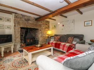 un salon avec un canapé et une cheminée dans l'établissement Chenalls Cottage, à Helston