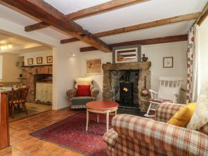 un salon avec une cheminée et une table dans l'établissement Chenalls Cottage, à Helston