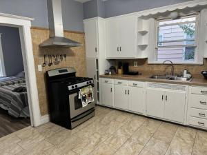 a kitchen with white cabinets and a stove and a sink at Large family home Near NYC in Passaic