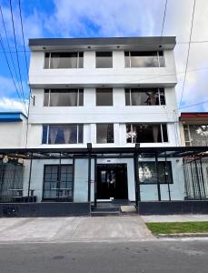 a tall white building with windows on a street at Hotel Embajada 44 in Bogotá
