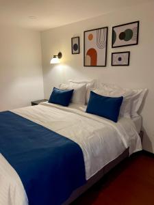 a bedroom with a large bed with blue and white pillows at Hotel Embajada 44 in Bogotá +148 photos
