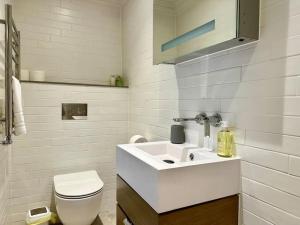 a white bathroom with a toilet and a sink at Cute Studio Basement Flat Richmond in Richmond upon Thames