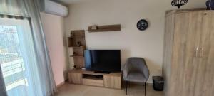 a living room with a television and a chair at Myrteni studio II in Nea Peramos