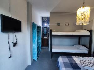 Una habitación con dos literas y un televisor de pantalla plana. en Coliving Porto de Galinhas, en Porto de Galinhas