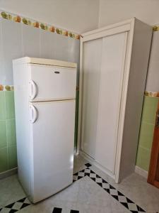 a white refrigerator in a kitchen with a checkered floor at Logement climatisé proche de Fès in El Harmiine