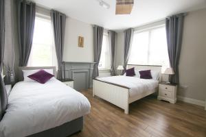 two beds in a bedroom with two windows at Millmasters House B&B at the Riverbank Restaurant in Drumahayre