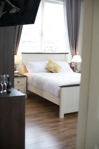 a bedroom with a white bed and a window at Millmasters House B&B at the Riverbank Restaurant in Drumahayre