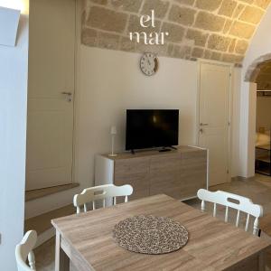 einen Tisch und Stühle im Wohnzimmer mit einem TV in der Unterkunft EL-MAR housea exclusive terrace, sea view in Polignano a Mare