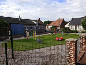 a fence in a yard with a playground at La maison d'Arthur et Armelène in Rely