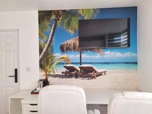 a living room with a tv on a beach with two chairs at Sunny Waves in Northampton