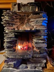 a stone fireplace with a fire in it at Lapland Chalet Lomalaavu in Suomutunturi