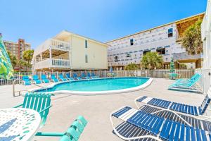a swimming pool with blue chairs and a building at Moonraker 25 in Gulf Shores