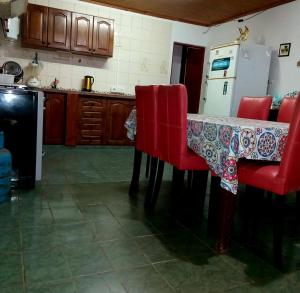 a kitchen with a table with red chairs and a refrigerator at Casa Marconi in Posadas