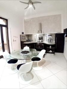 a kitchen with a glass table and white chairs at Casa vacanze Emma Siracusa Canicattini Bagni in Canicattini Bagni