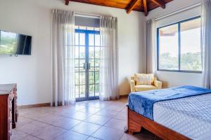 Un dormitorio con una cama y un televisor y ventanas. en Casa Wow, en Quepos