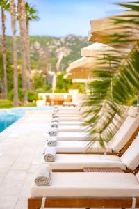 a row of lounge chairs next to a swimming pool at Hotel Corsica & Spa Serena in Calvi