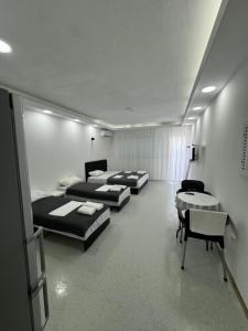 a room with three beds and a table and chairs at Apartmani MILIC in Kotor