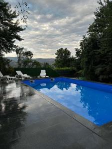 a large blue swimming pool with chairs and trees at Villa La Vida in Sarajevo