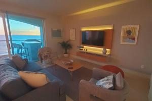 a living room with a couch and a television at BEACH FRONT CONDO, PRIVATE BEACH and AMAZING VIEWS!! in Los Cuatro Hermanos