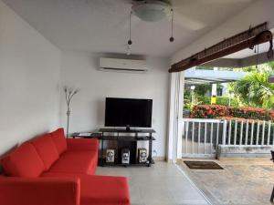 a living room with a red couch and a television at occidente Santa Fe de Antioquia sol y playa in Santa Fe de Antioquia