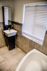 a bathroom with a tub and a sink and a window at Nauntons Guest House & Wedding Venue in Ladysmith