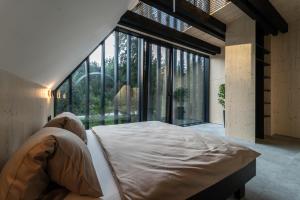 a bedroom with a large bed and large windows at Pine chalet in Smižany