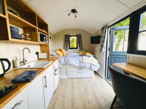 a small kitchen with a bed in a tiny house at Herdie Hideaway - Shepherds Hut in Wigton