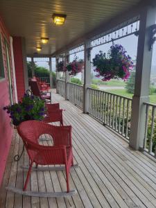 a porch with chairs and flowers on a house at Cranberry Cove Inn in Louisbourg