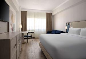 a hotel room with a large white bed and a desk at Sonesta White Plains Downtown in White Plains