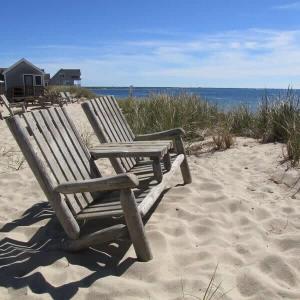 a wooden bench sitting on the sand at the beach at Peaceful Waterfront Beach Cottage! in Truro +5 photos