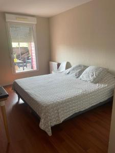 ein Schlafzimmer mit einem großen Bett mit Fenster in der Unterkunft Appartement 2 chambres in Artigues-près-Bordeaux