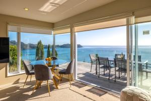 a dining room with a view of the ocean at Onetangi Clifftop, Onetangi - Be My Guest Waiheke in Onetangi
