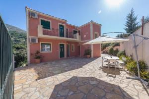 a patio in front of a house with an umbrella at Myrtos Cottages Kefalonia in Divarata