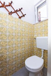 a bathroom with a white toilet and yellow tiles at Apartments with a parking space Pirovac, Sibenik - 13201 in Pirovac