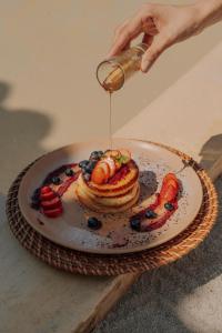 a person pouring syrup onto a plate of pancakes and fruit at Hotel Tahiti in Puente Iglesias