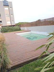 a wooden deck with a swimming pool in a backyard at Depto Los Pinos in Ostende
