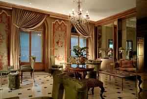 ein Wohnzimmer mit Kronleuchter, Tisch und Stühlen in der Unterkunft Hotel d'Angleterre in Genf