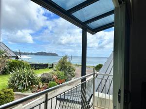 Una vista del océano desde el balcón de una casa. en Beachfront on Waiheke, en Onetangi