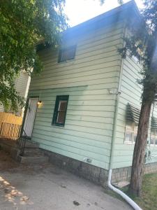 a house with a green siding and a tree at Magnolia APT 1 in Lansing