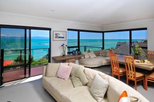 a living room with a couch and a table with a view at Ocean Dreaming - Nelson Waterfront in Nelson