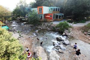 a group of people standing in a river near a house at gapyeong ceongpyeongmulsori pensyeon in Gapyeong