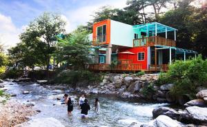a group of people in a river in front of a house at gapyeong ceongpyeongmulsori pensyeon in Gapyeong