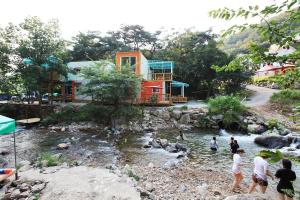 a group of people standing in a river with a house at gapyeong ceongpyeongmulsori pensyeon in Gapyeong