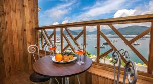 einen Tisch mit einem Obstteller und Weingläsern auf dem Balkon in der Unterkunft Geojae Beach Maru Pension in Geoje