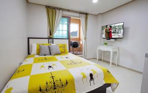 a bedroom with a bed with a yellow and white comforter at Kangchon Pine Tree Pension in Chuncheon