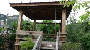 a wooden gazebo with a swing at Buan sukranjeong pension in Buan