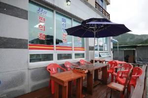 a wooden table with red chairs and an umbrella at Yeosu Court Pension in Yeosu