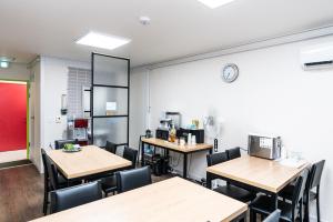 a classroom with tables and chairs and a clock on the wall at Jellyfish Pension in Samcheok +1 photo