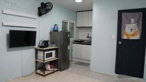 a kitchen with a refrigerator and a tv and a door at Gapyeong Gumuchon Amusement Park Pension in Gapyeong